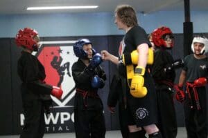 Young karate students preparing for belt testing in protective gear, showing karate belt levels explained through discipline and grading requirements.