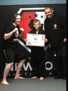 Karate student celebrating a belt promotion with instructors, illustrating karate belt levels explained through dedication, achievement, and consistent training.