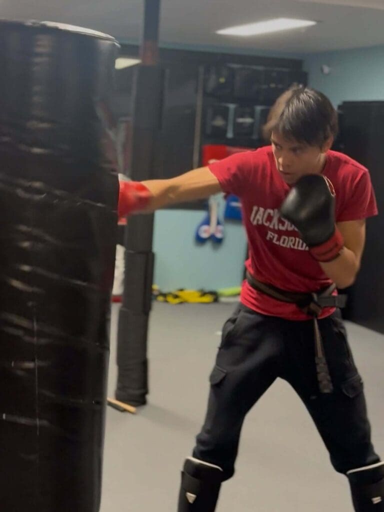 Teen boxer punching a heavy bag during a martial arts training session, teen self defense safety habits